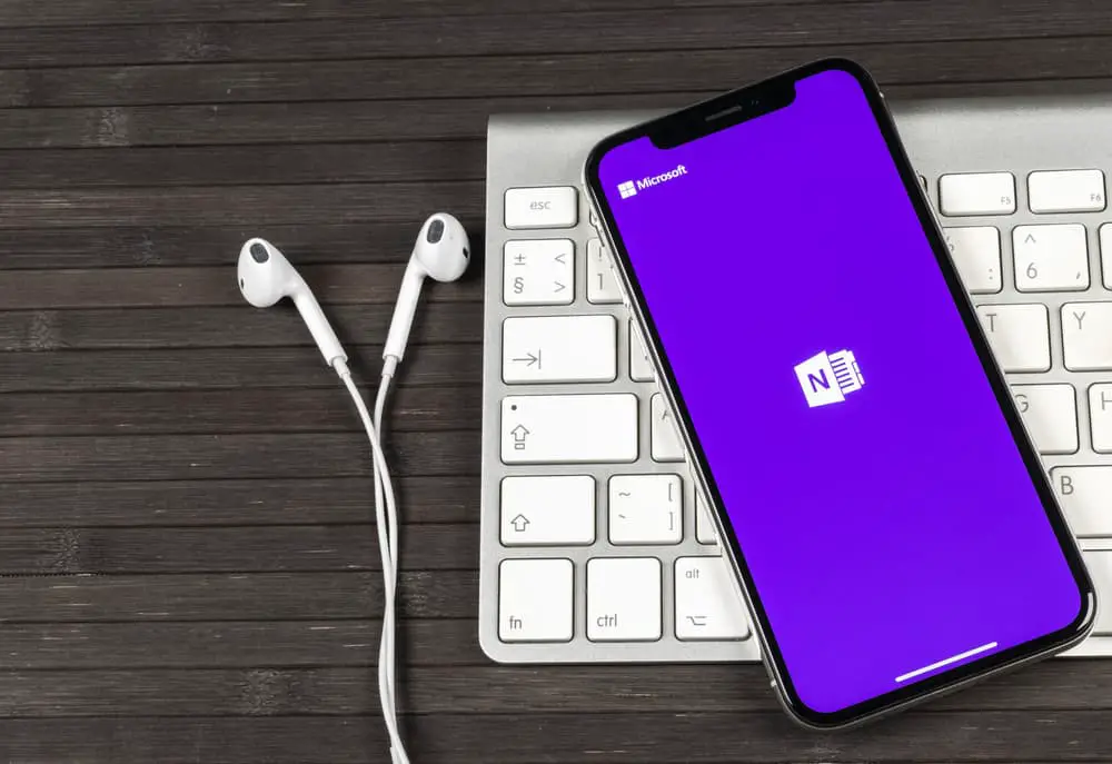 OneNote on a smartphone on a keyboard with earbuds